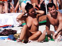 Lachend met witte hoed op een druk topless strand in de namiddag