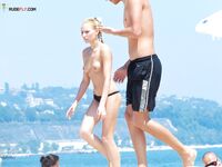Lachend met witte hoed op een druk topless strand in de namiddag
