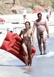 Durch den belebten Strand oben ohne – Sandalen in der Hand