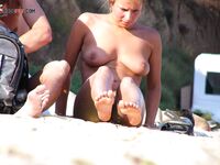 Bronzage nu sur le sable, pieds en avant, cheveux relevés