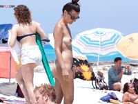 Cruza una playa nudista soleada entre paraguas amarillos y azules
