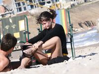 Adjusting a Sandal While Seated on the Beach Sand