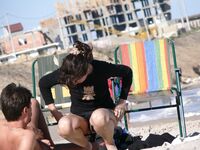 Adjusting a Sandal While Seated on the Beach Sand