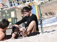 Adjusting a Sandal While Seated on the Beach Sand