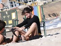 Adjusting a Sandal While Seated on the Beach Sand