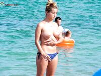 Topless in Shallow Turquoise Surf With Her Hair in a High Bun