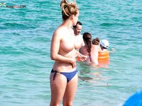 Topless in Shallow Turquoise Surf With Her Hair in a High Bun