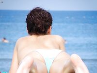 Sitting Topless by the Sea With Arms Resting on Her Knees