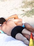 עומדת בגלי הרדודים בחוף עירום כשגלים קטנים נשברים