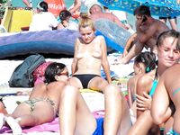Examining a Held Item Topless on the Beach in Red-Tie Bottoms