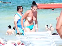 Examining a Held Item Topless on the Beach in Red-Tie Bottoms
