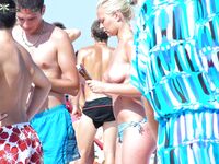 Examining a Held Item Topless on the Beach in Red-Tie Bottoms