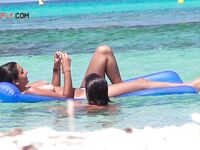 Two Bathers Share a Blue Inflatable Mat in Turquoise Shallows