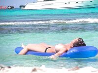Two Bathers Share a Blue Inflatable Mat in Turquoise Shallows