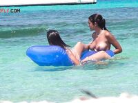 Two Bathers Share a Blue Inflatable Mat in Turquoise Shallows
