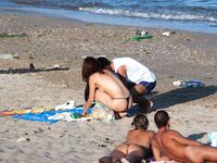 Nude Beach Couple Sorting Towels Beside a Backpack