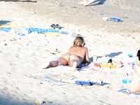 Nude Beach Couple Sorting Towels Beside a Backpack