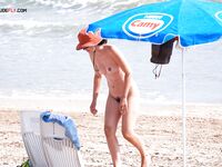 Feeling the heat of the sand while lounging topless at a private sandy cove. 3