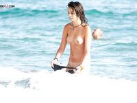 A lady enjoying a tropical-style waterfront in a traditional, topless European manner. 3