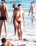 Úsměv na květinovém ručníku s pokrčenými koleny na nudistické pláži