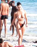 Úsměv na květinovém ručníku s pokrčenými koleny na nudistické pláži