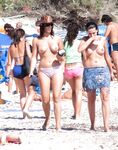 Úsměv na květinovém ručníku s pokrčenými koleny na nudistické pláži