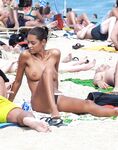 Úsměv na květinovém ručníku s pokrčenými koleny na nudistické pláži