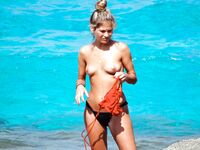 Her Turquoise Sarong Opens Wide Against Sunlit Rocky Shoreline
