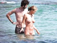 Two Naturists Pause Mid-Wade in Calm Shallow Sea Water