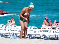 Such a cutie is a rare thing on a naturist strand. She was well protected by her companion.