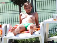 Topless opalování na pruhovaném ručníku vedle lehátka u bazénu