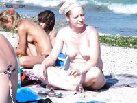Two Nudists Standing Together by Beach Rocks