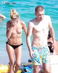 Black Bikini Bottoms and Floral Swim Shorts on Bright Topless Sand