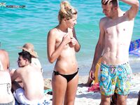 Black Bikini Bottoms and Floral Swim Shorts on Bright Topless Sand