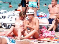 Black Bikini Bottoms and Floral Swim Shorts on Bright Topless Sand