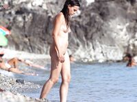 A lady enjoying a cold drink while sunbathing topless on the warm shore. 3