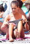 A lady enjoying a cold drink while sunbathing topless on the warm shore. 3