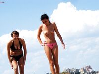 Laag geknield in roze bikinibroekje op warm topless strandzand