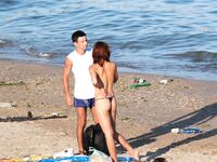 Laag geknield in roze bikinibroekje op warm topless strandzand