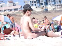 Klobouk v alpském stylu a piercing v pupíku na teplém písku nudistické pláže
