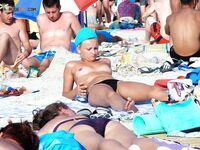 . A model enjoying the intense heat of the sun in a relaxed, topless style. 2