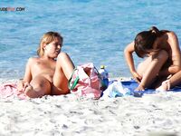 Poklek na modré osušce u tyrkysové vody na nudistické pláži