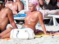 Two Women Topless at the Beach Near Sun Loungers