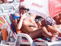 Lotion insmeren naast een wit lamellen-windbreuk op het zand