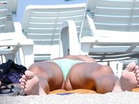 Enjoying the rhythmic sound of the waves while relaxing topless on a private towel.