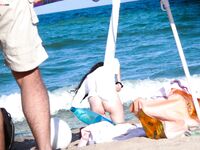 The natural light of the shore accentuating the beauty of a topless model on the sand.