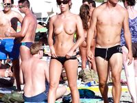 Setřásá vodu z ruky na mokré nudistické pláži