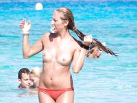 Turquoise Sea and Rocks Frame a Topless Beach Bather