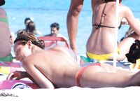 Turquoise Sea and Rocks Frame a Topless Beach Bather