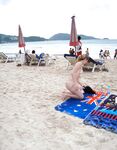 Turquoise Sea and Rocks Frame a Topless Beach Bather